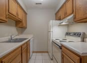 Thumbnail 16 of 27 - Omaha, NE Woodland Pines Apartments. A kitchen with wooden cabinets and white appliances
