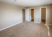 Thumbnail 20 of 34 - an empty living room with carpet and a door to a bathroom. Omaha, NE Evergreen Terrace Apartments