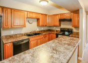 Thumbnail 18 of 34 - a kitchen with granite counter tops and wooden cabinets. Omaha, NE Evergreen Terrace Apartments