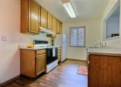 Thumbnail 27 of 31 - A kitchen with white appliances and wooden cabinets. Fargo, ND Oxford Apartments.