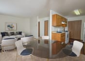 Thumbnail 6 of 20 - Fargo, ND Park Circle Apartments. a living room with a glass table and chairs and a kitchen with a stove and oven