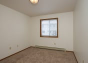 Thumbnail 16 of 20 - the living room of an empty home with carpet and a window. Fargo, ND Park Circle Apartments.