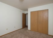 Thumbnail 18 of 20 - a bedroom with a closet and a door to a hallway. Fargo, ND Park Circle Apartments.