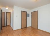 Thumbnail 15 of 20 - the living room of an empty apartment with wood flooring and three doors. Fargo, ND Park Circle Apartments.