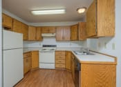 Thumbnail 14 of 20 - a kitchen with white appliances and wooden cabinets. Fargo, ND Park Circle Apartments.