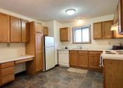 Thumbnail 10 of 23 - Kitchen with wooden cabinets and a white refrigerator at Parkwest Gardens West Fargo, ND 58078
