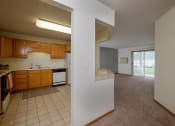 Thumbnail 7 of 15 - A kitchen with a living room in the background. Pinehurst Apartments | 2 Bedroom