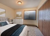 Thumbnail 2 of 26 - a bedroom with a bed and a dresser and a window. Fargo, ND Prairiewood Meadows Apartments