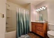 Thumbnail 10 of 21 - a bathroom with a shower toilet and sink and a mirror. Fargo, ND Prairiewood Courts Apartments