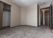 Thumbnail 11 of 25 - Grand Forks Primrose Apartments a small bedroom with two doors and a carpeted floor