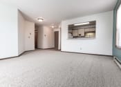 Thumbnail 16 of 25 - Grand Forks Primrose Apartments. An empty living room with a kitchen in the background