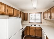 Thumbnail 17 of 28 - Grand Forks, ND Richfield Apartments. A kitchen with white appliances and wooden cabinets