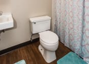 Thumbnail 9 of 23 - Grand Forks, ND Riverwood Apartments.  A bathroom with a shower curtain and a toilet and a sink
