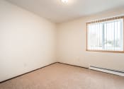 Thumbnail 8 of 23 - Grand Forks, ND Riverwood Apartments. A bedroom with carpeted floors and a window.