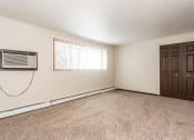 Thumbnail 12 of 23 - Grand Forks, ND Riverwood Apartments. A living room with an air conditioner and a door