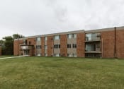 Thumbnail 22 of 23 - Grand Forks, ND Riverwood Apartments. A brick apartment building with a large grass yard