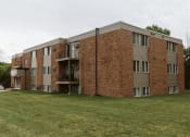 Thumbnail 21 of 23 - Grand Forks, ND Riverwood Apartments. A red brick apartment building with a green yard