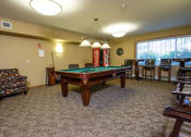 Thumbnail 18 of 21 - a pool table with chairs around it and a window. Fargo, ND Crossroads Apartments