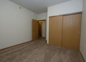 Thumbnail 4 of 23 - a bedroom with a door to a hallway and a closet. Fargo, ND North Sky Apartments
