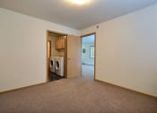 Thumbnail 8 of 18 - a bedroom with a door to a laundry room with a washer and dryer. Moorhead, MN Sandy Creek Apartments
