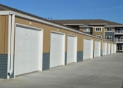 Thumbnail 18 of 18 - a row of garages with white doors in front of an apartment building. Moorhead, MN Sandy Creek Apartments