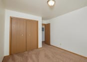 Thumbnail 21 of 22 - a spacious living room with carpet and a door to a bedroom. Fargo, ND Sargent Apartments