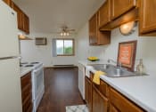 Thumbnail 18 of 22 - a kitchen with wooden cabinets and white appliances and a sink. Fargo, ND Sargent Apartments