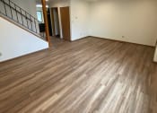 Thumbnail 22 of 28 - An empty living room with wooden floors and white walls