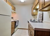 Thumbnail 14 of 17 - a kitchen with white appliances and wooden cabinets. Fargo, ND Southgate Apartments