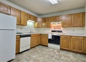 Thumbnail 15 of 17 - a kitchen with white appliances and wooden cabinets. Fargo, ND Southgate Apartments