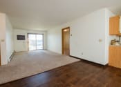 Thumbnail 12 of 19 - a living room with a glass sliding door and bedroom doors on the left and right. Fargo, ND South Pointe Apartments