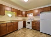 Thumbnail 13 of 14 - a kitchen with white appliances and wooden cabinets. Fargo, ND Spring Apartments