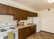 Thumbnail 8 of 10 - a kitchen with white appliances and wooden cabinets and a white refrigerator. Grand Forks, ND Stanford Court Apartments
