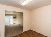 Thumbnail 6 of 10 - an empty living room with wood flooring and a door to a hallway. Grand Forks, ND Stanford Court Apartments
