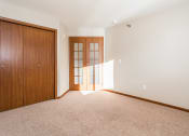 Thumbnail 11 of 19 - Grand Forks Sterling Pointe Apartments. A bedroom with French doors and a closet.
