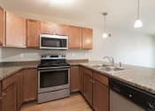 Thumbnail 11 of 16 - Kitchen with Microwave and Stove at Stonefield Apartments in Bismarck, ND