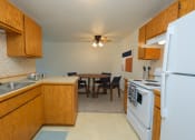 Thumbnail 4 of 10 - Fargo, ND Sugarplum Apartments. A kitchen and dining room. The dining room has a table with four chairs around it with a ceiling fan and light directly above it.