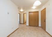 Thumbnail 10 of 20 - Living room and hallway with two doors and a door to a closet at Sunset Ridge Apartments in 58503 ND