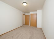Thumbnail 18 of 28 - a spacious living room with carpet and a door to a bedroom. Fargo, ND Thunder Creek Apartments | KitchenFargo, ND Thunder Creek Apartments