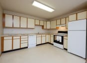 Thumbnail 14 of 28 - an empty kitchen with white appliances and wooden cabinets. Fargo, ND Thunder Creek Apartments
