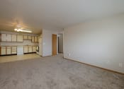 Thumbnail 13 of 28 - the living room and kitchen of an apartment with carpeting and a ceiling fan. Fargo, ND Thunder Creek Apartments