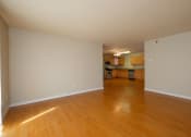 Thumbnail 8 of 28 - an empty living room with a hardwood floor and a kitchen in the background. Fargo, ND Thunder Creek Apartments