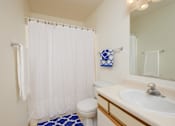 Thumbnail 11 of 16 - a bathroom with a white shower curtain and a sink and a toilet. Fargo, ND Twin Parks Apartments.