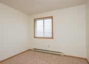 Thumbnail 9 of 16 - a bedroom with white walls and a window and a carpet. Fargo, ND Twin Parks Apartments.