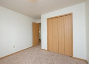 Thumbnail 10 of 16 - Fargo, ND Twin Parks Apartments. a bedroom with two closets and a carpeted floor