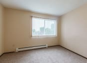 Thumbnail 5 of 6 - Grand Forks, ND Twin Drive Apartments. A bedroom with a window and a carpeted floor