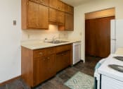 Thumbnail 9 of 34 - a kitchen with white appliances and wooden cabinets. Fargo, ND Islander Apartments