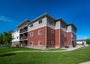 Thumbnail 43 of 45 - a modern apartment building with a green lawn and a blue sky