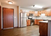 Thumbnail 27 of 45 - a kitchen with wooden cabinets and a stainless steel refrigerator. Fargo, ND Urban Plains Apartments