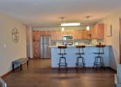 Thumbnail 11 of 45 - an empty living room with a kitchen with a bar and stools. Fargo, ND Urban Plains Apartments
